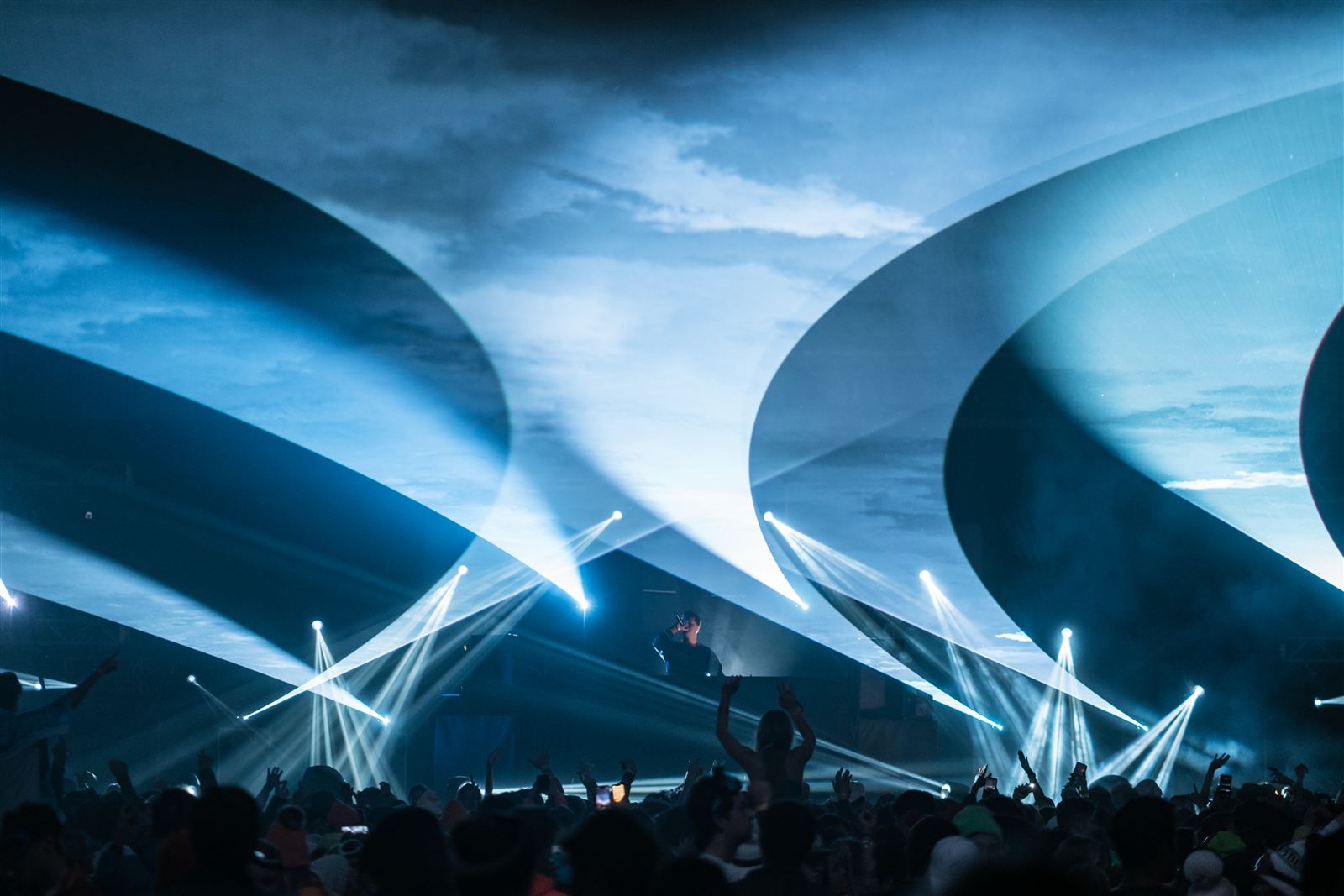 EDM festival stages, beam looks against a dusk sky